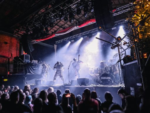 Eine Band spielt live auf einer Bühne vor begeistertem Publikum.
