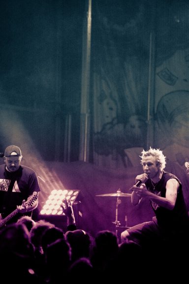 Zwei Musiker performen auf der Bühne vor einem jubelnden Publikum in bunten Lichtern.